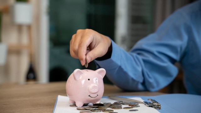 Article thumbnail: Man putting a coin into a pink piggy bank concept for savings and finance