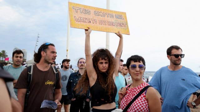 Article thumbnail: A demonstrator holds up a banner as people protest against mass tourism in Barcelona, Spain, July 6, 2024. The Catalan capital received more than 12 million tourists in 2023 and expects more in 2024. REUTERS/Bruna Casas