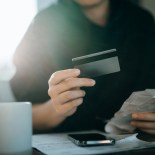 Article thumbnail: Cropped shot of young Asian woman holding credit card and expense receipts, handing personal banking and finance at home. Planning budget, calculating expenses and managing financial bills. Home budgeting. Home finances. Digital banking habits