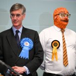 Article thumbnail: BATH, ENGLAND - JULY 05: Conservative candidate Jacob Rees-Mogg stands next to Barmy Brunch from The Official Monster Raving Loony Party during the declaration for the North East Somerset constituency at the University of Bath campus, on July 05, 2024 in Bath, England. The incumbent MP for North East Somerset is the Conservative Jacob Rees-Mogg. In Boris Johnson's government, he held the position of Secretary of State for Business, Energy and Industrial Strategy. (Photo by Finnbarr Webster/Getty Images)